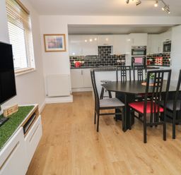 A kitchen with black dining table and chairs a television and white cabinets at Tremar in Carbis Bay