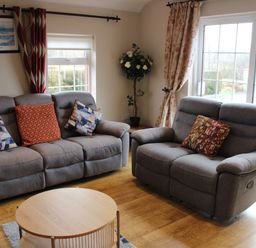 A living room with two gray sofas and a round wooden coffee table at Ellens Cottage in Mount Charles County Donegal
