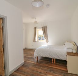 A bedroom with a single bed beside a dresser and a window with curtains at Macreddin Rock Holiday Cottage Macreddin Aughrim County Wicklow