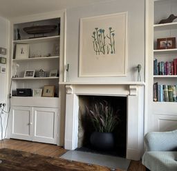 A living room with a bookshelf, fireplace, and armchair at Brock Cottage West Bay