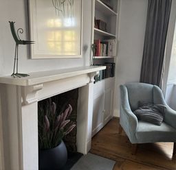 A living room with a fireplace and bookshelf at Brock Cottage in West Bay
