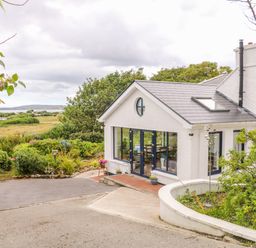 Exterior of a white house with large windows and a garden path at The Mermaid in Dungloe County Donegal