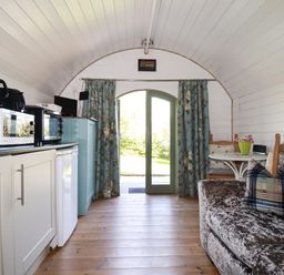 A small living area with kitchen appliances a sofa and a table with chairs at The Lamb Shack in St Teath