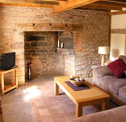 A living room with a stone wall fireplace a wooden coffee table and a sofa at Point Cottage in Preston-on-Wye near Hereford