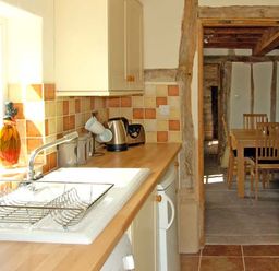A kitchen with a sink drying rack kettle and toaster leading to a dining area at Point Cottage Preston-on-Wye near Hereford