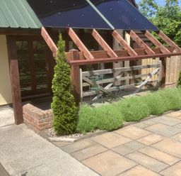 An outdoor patio area with wooden fence and green plants at The Forge in Shipham