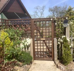 A wooden garden gate with climbing white flowers and surrounding bushes at The Forge in Shipham