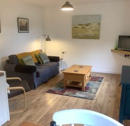 A living room with sofa armchair wooden coffee table and television at Mendip Cottage in Shipham