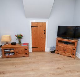 A snug with a television and wooden furniture at Hasting Dairy in North Sunderland near Seahouses
