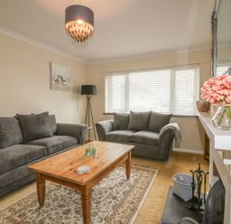 A living room with two gray sofas a wooden coffee table and a lamp at Dune Haven in Goonhavern near Perranporth