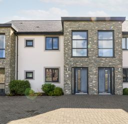 A modern two-story stone and white facade building with numbered blue front doors and windows at Cysgod Y Capel in Benllech