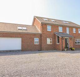 A two-story brick house with a large garage and gravel driveway at Cadwgan in Aberporth