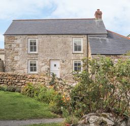 A stone house with a slate roof surrounded by a stone wall and garden in Morvah