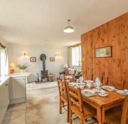 A kitchen and dining area with a wooden table set for tea and a wood-paneled wall at The Old Laundry in North Tawton