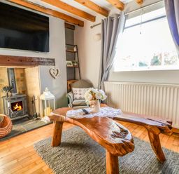 A living room with a fireplace and wooden table at Woodland Cottage in Garth