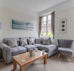A living room with gray sofa and chair wooden coffee table and windows with curtains at Nuke in Weymouth