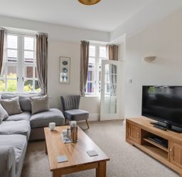 A living room with a gray sofa a wooden coffee table a gray chair and a television on a wooden stand at Nuke in Weymouth