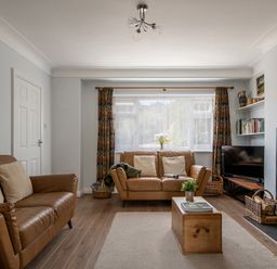 A living room with brown leather sofas a wooden coffee table a fireplace and a television at Heddfan in Conwy