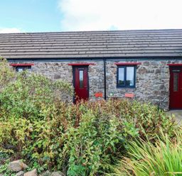 An outdoor area with stone walls and doors at Cattle Shed near Narberth