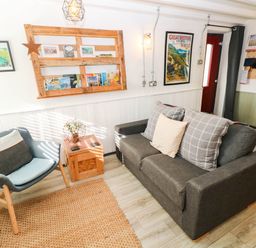 A living room with sofa, armchair, and shelf at Milking Shed near Narberth