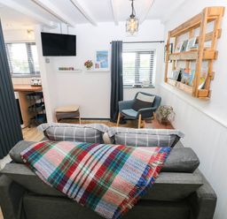 A living room with a sofa, armchair, and television at Milking Shed near Narberth