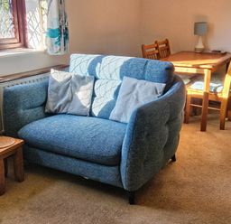 A living room with a sofa and dining table at Chiffchaff in Padstow