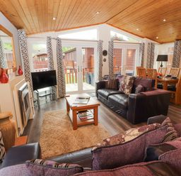 A living room with sofas coffee table and dining table near windows and doors at Fell View Lodge in Troutbeck