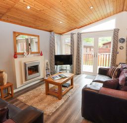 A living room with sofas coffee table fireplace and television at Fell View Lodge in Troutbeck