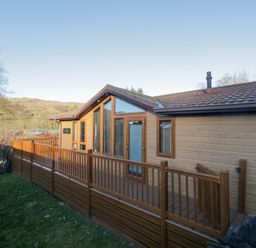 A cabin exterior with a wooden deck and large windows at Heights View