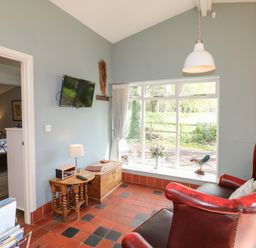 A room with red leather chairs wooden tables and a window with a view at Hen House View in Rugeley