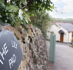 A stone wall with a sign saying The Lily Pad and a driveway leading to a house at The Lily Pad in Camborne