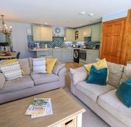 A living room with a sofa and kitchen area at Waterhead Cottage in Ecclerigg, near Troutbeck Bridge