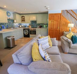 A living room with a kitchen area and seating at Waterhead Cottage in Ecclerigg, near Troutbeck Bridge