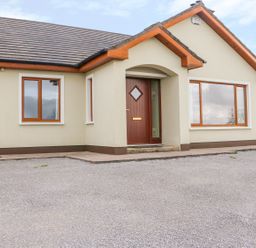 Front view of a single-story house with multiple windows and a wooden front door at Rossanean in Farranfore near Killarney County Kerry