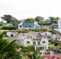 A view of houses on a hillside with greenery and trees at Blue Bay Beach House in Mawgan Porth
