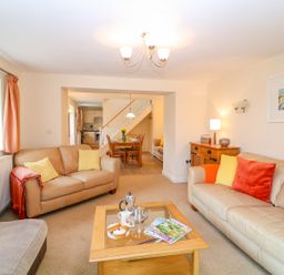 A living room with two beige sofas and a wooden coffee table with magazines and tea set at Cornflower Cottage in St Columb Major