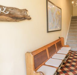 A hallway with a wooden bench and cushions a staircase and a world map on the wall at Angorfa in Llanbedr