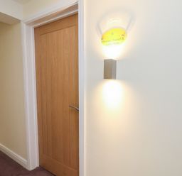 A hallway with a door and wall light fixture at Premier, Transit & Lady Hilda @ Engine Shed in Whitby