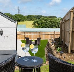 A garden with wicker chairs small table and glasses of water with lemon at Be Our Guest Cottage in Chacewater near Truro