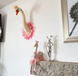 A wall with swan decorations and a silver statue on a stone mantel a dandelion framed picture and a tv nearby at Be Our Guest Cottage in Chacewater near Truro