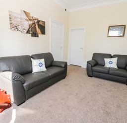 A living room with two dark sofas and nautical themed cushions at Sailors Lodge in Filey