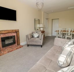 A living room with a sofa armchair and dining table with chairs at Coquet View Apartment in Warkworth