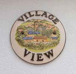 A round plaque with a village scene and the words Village View on a textured wall at Village View in Burton Bradstock