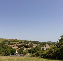 A village with houses trees and a church tower surrounded by fields at Village View in Burton Bradstock