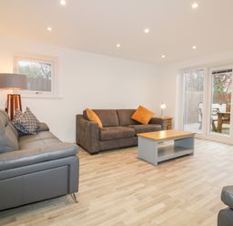 A living room with sofas coffee table lamp and glass doors opening to a garden at Lily Cottage in Camelford