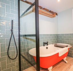 A bathroom with a red clawfoot bathtub and a glass shower partition at Tickmorend Farm in Nailsworth