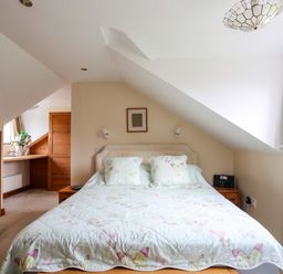 A bedroom with a double bed and butterfly patterned bedding at Barras Cottage in Brynsiencyn