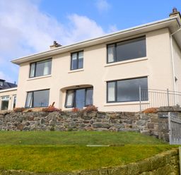 A house with windows and a stone wall at Bryn Deryn in Criccieth