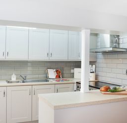 A kitchen with white cabinets a countertop with bread vegetables and kitchen appliances at Brook Cottage in Criccieth