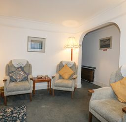 A sitting room with armchairs, side tables, lamps and framed pictures at Bro Dawel in Beaumaris